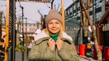 hermosa joven rubia mira con una sonrisa mientras está de pie al aire libre foto