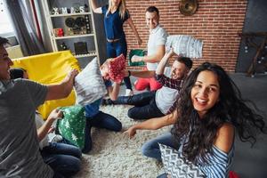 Crazy young best friends fighting pillows at home. Mixed race group of people. Concept  entertainment and lifestyle photo