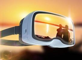 auriculares de realidad virtual, doble exposición, pareja romántica en la playa con un colorido fondo de puesta de sol foto