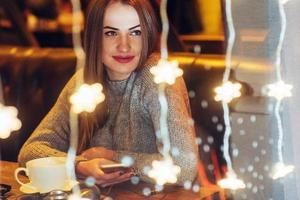 Young beautiful woman sitting in cafe, drinking coffee. Christmas, new year, Valentines day, winter holidays concept photo