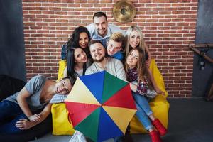 Group portrait of multi-ethnic boys and girls with colorful fashionable clothes holding friend posing on a brick wall, Urban style people having fun, Concepts about youth togetherness lifestyle photo