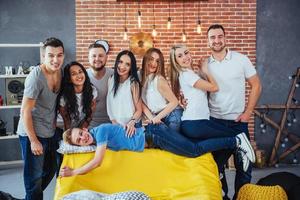 Group portrait of multi-ethnic boys and girls with colorful fashionable clothes holding friend posing on a brick wall, Urban style people having fun, Concepts about youth togetherness lifestyle photo