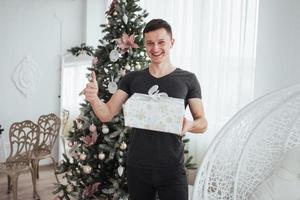hombre sosteniendo una caja de regalo y sonriendo. concepto del día de navidad. hombre guapo en camisa con caja de regalo presente foto