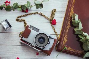 Retro camera roll photo film and flowers on white wooden background