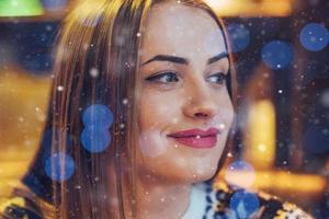 hermosa mujer joven sentada en la cafetería, bebiendo café. modelo mirando hacia arriba. navidad, año nuevo, día de san valentín, concepto de vacaciones de invierno foto