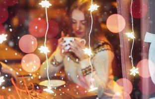 Young beautiful woman sitting in cafe, drinking coffee. Christmas, new year, Valentines day, winter holidays concept photo