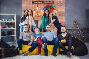 Group portrait of multi-ethnic boys and girls with colorful fashionable clothes holding friend posing on a brick wall, Urban style people having fun, Concepts about youth togetherness lifestyle photo