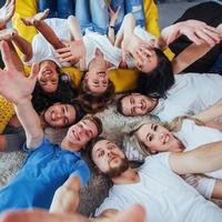 grupo de jóvenes hermosos haciendo selfie tirados en el suelo, mejores amigos niñas y niños juntos divirtiéndose, planteando un concepto de estilo de vida emocional foto