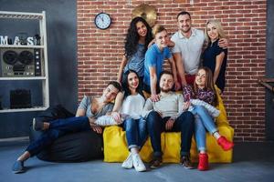 Group portrait of multi-ethnic boys and girls with colorful fashionable clothes holding friend posing on a brick wall, Urban style people having fun, Concepts about youth togetherness lifestyle photo