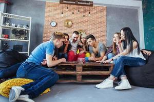 grupo de amigos creativos sentados en la mesa de madera. gente divirtiéndose mientras juega al juego de mesa. foto