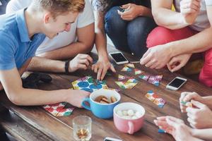 Top view creative photo of friends sitting at wooden table.  having fun while playing board game