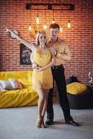 Young couple dancing latin music. Bachata, merengue, salsa. Two elegance pose on cafe with brick walls photo