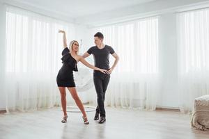 Young couple dancing latin music. Bachata, merengue, salsa. Two elegance pose on white room photo