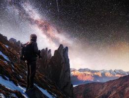 paisaje con vía láctea, estrellas del cielo nocturno y silueta de un fotógrafo de pie en la montaña. foto