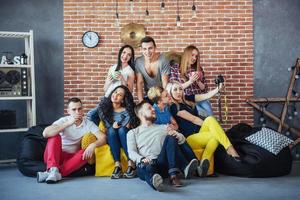 retrato grupal de niños y niñas multiétnicos con ropa colorida de moda sosteniendo a un amigo posando en una pared de ladrillo, gente de estilo urbano divirtiéndose, conceptos sobre el estilo de vida de la unión juvenil foto