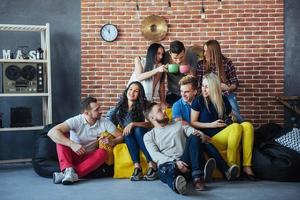 Group portrait of multi-ethnic boys and girls with colorful fashionable clothes holding friend posing on a brick wall, Urban style people having fun, Concepts about youth togetherness lifestyle photo