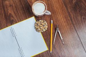 vista superior del cuaderno, papelería, herramientas de dibujo y algunas tazas de café. foto