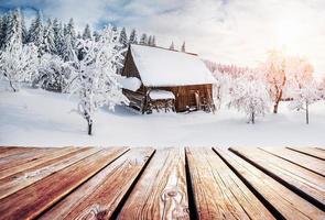 paisaje de montañas de invierno con un bosque nevado y una cabaña de madera foto