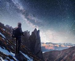 paisaje con vía láctea, estrellas del cielo nocturno y silueta de un fotógrafo de pie en la montaña. foto