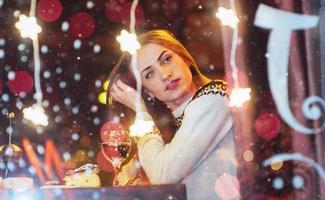 hermosa mujer joven sentada en el café, bebiendo vino. navidad, año nuevo, día de san valentín, concepto de vacaciones de invierno foto