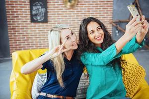 Two beautiful young woman doing selfie in a cafe, best friends girls together having fun, posing emotional lifestyle people concept photo