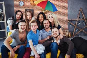 Group portrait of multi-ethnic boys and girls with colorful fashionable clothes holding friend posing on a brick wall, Urban style people having fun, Concepts about youth togetherness lifestyle photo