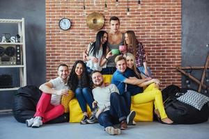 Group portrait of multi-ethnic boys and girls with colorful fashionable clothes holding friend posing on a brick wall, Urban style people having fun, Concepts about youth togetherness lifestyle photo