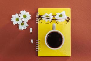Notebook, glasses and coffee on a brown background. photo