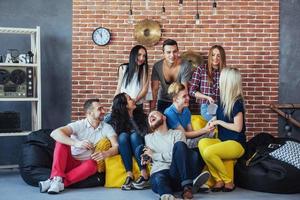 Group portrait of multi-ethnic boys and girls with colorful fashionable clothes holding friend posing on a brick wall, Urban style people having fun, Concepts about youth togetherness lifestyle photo