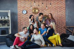 Group portrait of multi-ethnic boys and girls with colorful fashionable clothes holding friend posing on a brick wall, Urban style people having fun, Concepts about youth togetherness lifestyle photo