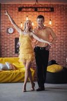 Young couple dancing latin music. Bachata, merengue, salsa. Two elegance pose on cafe with brick walls photo