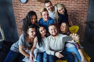 agrupar a hermosos jóvenes haciendo selfie en un café, mejores amigos niñas y niños juntos divirtiéndose, planteando un concepto de estilo de vida emocional foto