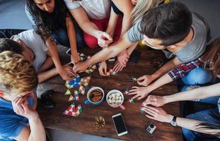 Top view creative photo of friends sitting at wooden table.  having fun while playing board game