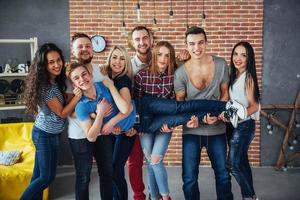 retrato grupal de niños y niñas multiétnicos con ropa colorida de moda sosteniendo a un amigo posando en una pared de ladrillo, gente de estilo urbano divirtiéndose, conceptos sobre el estilo de vida de la unión juvenil foto