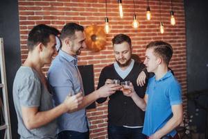 viejos amigos alegres se comunican entre sí con vasos de whisky en el pub. concepto de entretenimiento y estilo de vida foto