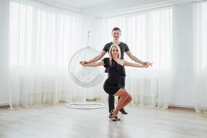 pareja joven bailando música latina. bachata, merengue, salsa. pose de dos elegancia en la habitación blanca foto