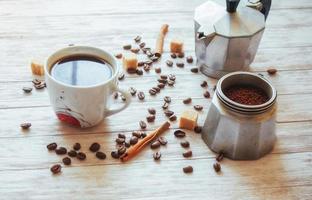 granos de café y una taza de café en la mesa al fondo foto