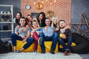 retrato grupal de niños y niñas multiétnicos con ropa colorida de moda sosteniendo a un amigo posando en una pared de ladrillo, gente de estilo urbano divirtiéndose, conceptos sobre el estilo de vida de la unión juvenil foto