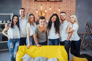 Group portrait of multi-ethnic boys and girls with colorful fashionable clothes holding friend posing on a brick wall, Urban style people having fun, Concepts about youth togetherness lifestyle photo