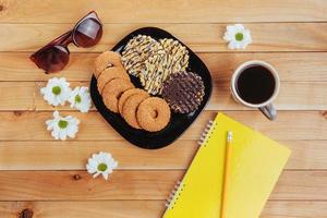 Coffee espresso stands on a wooden table with cookies, pad and pencil. photo