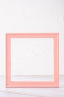 pastel pink picture frame with olive leaf on marble table with concrete wall photo