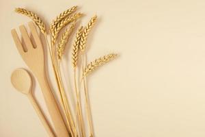 Several stalks of ripe wheat and wooden chef's fork and spoon. photo
