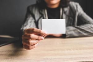 mujer de negocios sosteniendo y mostrando la tarjeta de visita blanca o el nombre de la tarjeta en blanco en las manos. plantilla para su diseño. maqueta de tarjeta de visita foto