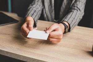 Business woman holding and giving white business card or blank card name in hands. Template for your design. Business card mock up photo