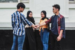 Group of young people putting their hands on top of each other. Students friends making a stack of hands, team handshake photo