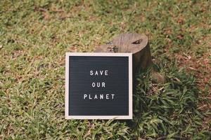 Felled tree and Quote on letter board says Save Our Planet over green grass background photo