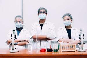 Group of scientist wearing protective mask and uniform posing with confidence photo