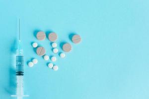 Top view of syringe or needle with tablet medicine isolated on blue background with copy space photo