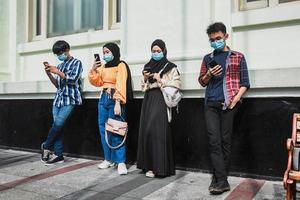 Group of young group people using mobile cell phones to watch content in the new normality time during coronavirus pandemic. Millennial generation people always connected concept photo