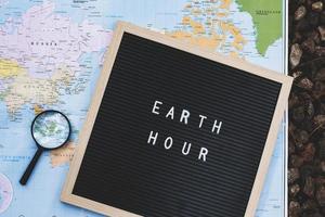 la cita en el tablero de cartas dice la hora de la tierra con una lupa en el mapa mundial